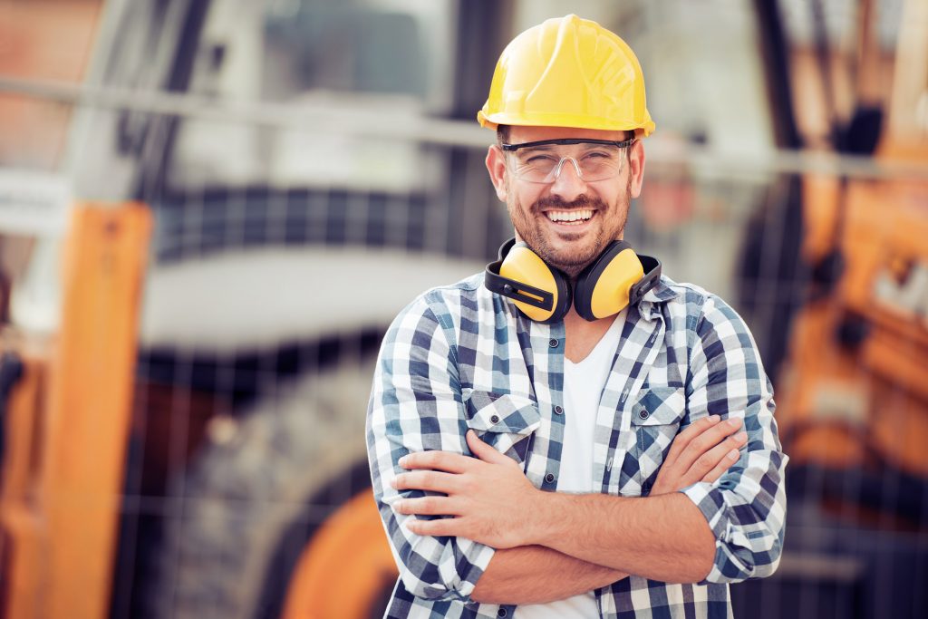 Construction Worker in Yellow Hard Hat and Safety Glasses Smiles Big