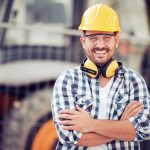 Construction Worker in Yellow Hard Hat and Safety Glasses Smiles Big